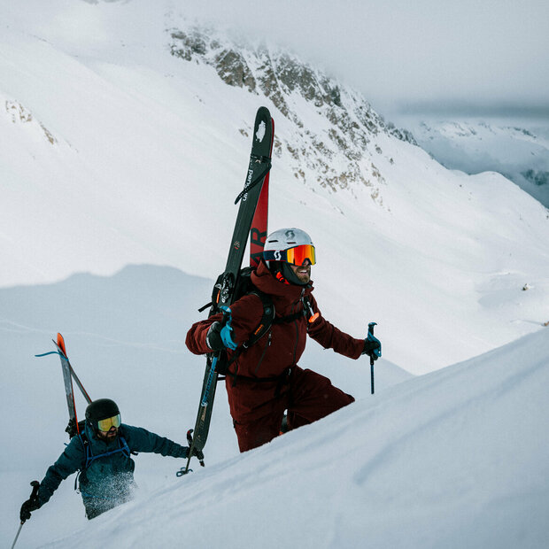 Das Ziel vor Augen. Zwei Skitourengeher befinden sich in einem Steilhang auf ihrer Skitour im Defereggental. Sie tragen ihre Tourenski am Rücken und blicken ihrem Ziel motiviert entgegen.