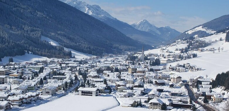 Sillian Ortsansicht von Sillian mit verschneiter Winterlandschaft und Blick auf die Sextener Dolomiten im Hintergrund.