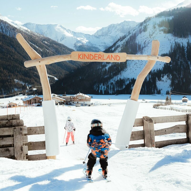 Kinderland Obertilliach Skifahren '22 Ein Kind passiert auf Ski den Eingang ins Kinderland im Familienskigebiet Golzentipp in Obertilliach.