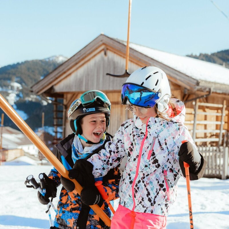 Kinderland Obertilliach Skifahren '22 Zwei Kinder lassen sich vom Schlepplift im Familienskigebiet Golzentipp in Obertilliach auf den Berg ziehen.
