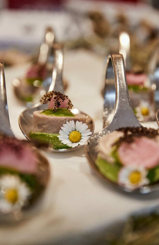 Haubenküche Gannerhof Haubenküche im Gannerhof - Gericht bestehend aus einem runden Fleischstück mit einer grünen Soße verziert mit einem Gänseblümchen auf einem Löffel angerichtet.