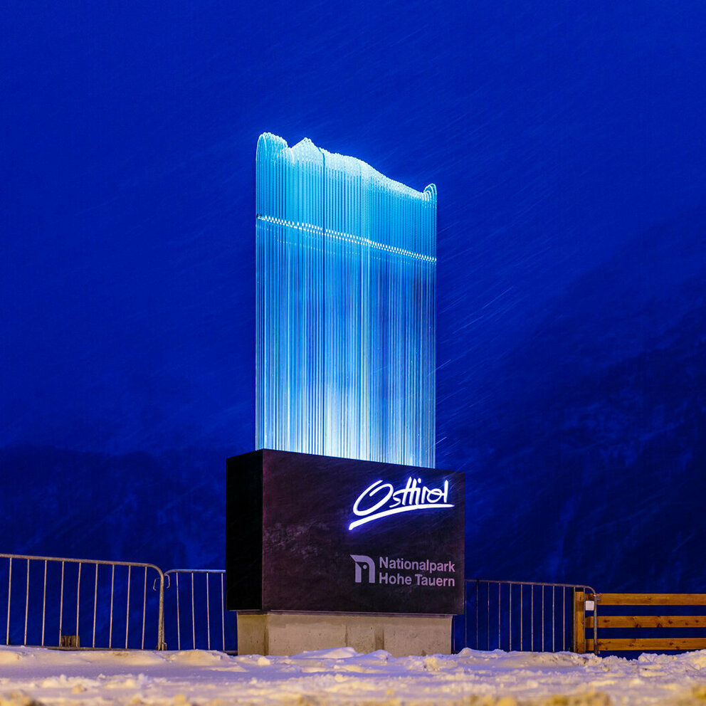 Das gläserne und im Dunkeln leuchtende Willkommensportal am Felbertauerntunnel bei Dämmerung.