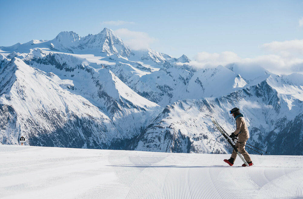 Skifahren mit Aussicht wie hier, im Großglockner-Resort Kals-Matrei. Winterliches Panorama mit dem Großglockner im Hintergrund und einem Skifahrer im Vordergrund, der sich gerade bereit macht, in seine Ski zu steigen.