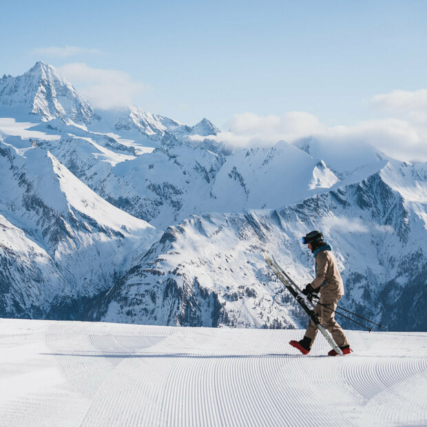 Winterliches Panorama mit dem Großglockner im Hintergrund und einem Skifahrer im Vordergrund, der sich gerade bereit macht, in seine Ski zu steigen.