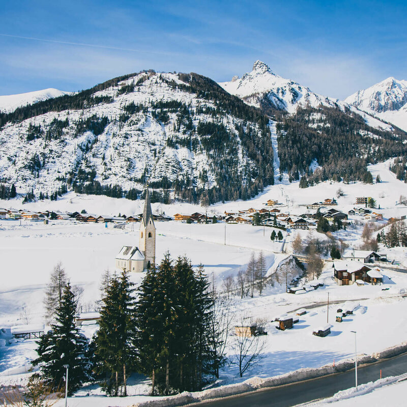 Kals Blick auf das verschneite Kals mit Kirche und Wohnhäusern, an einem sonnigen Tag.