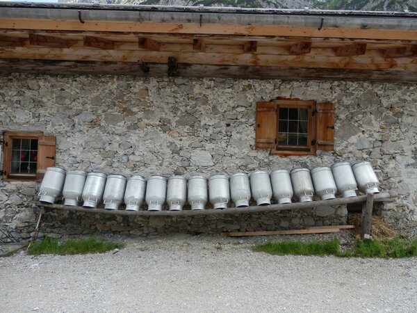 Rieplerhof - Nationalpark Regionsprodukte Milchkandeln hängen aufgereiht vor den Steinmauern des Rieplerhofs.