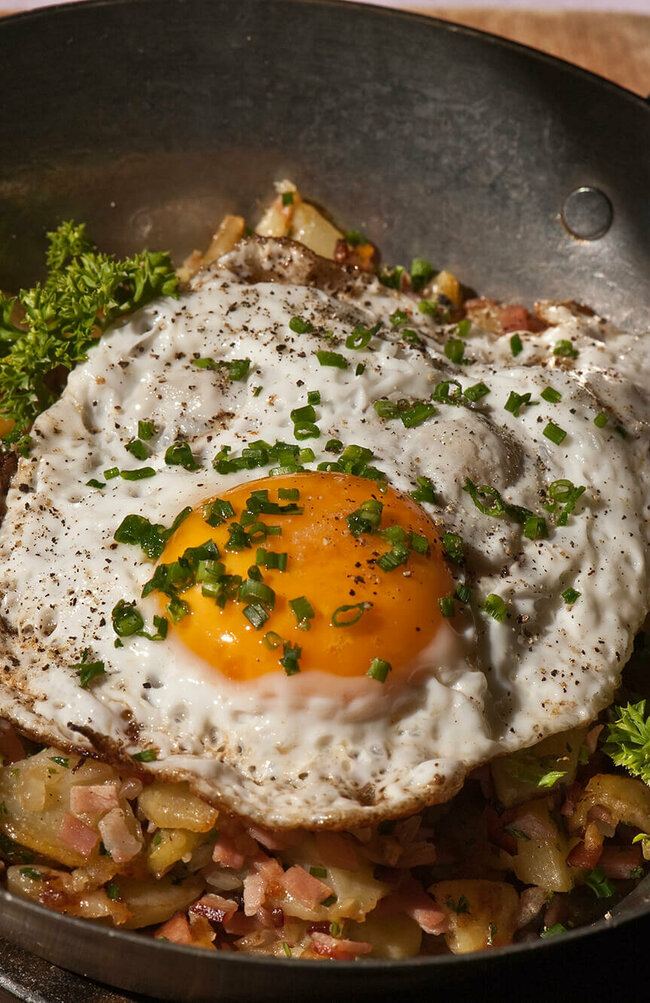 Tiroler Gröstl Tiroler Gröstl mit Spiegelei und Schnittlauch in einer kleine Eisenpfanne.