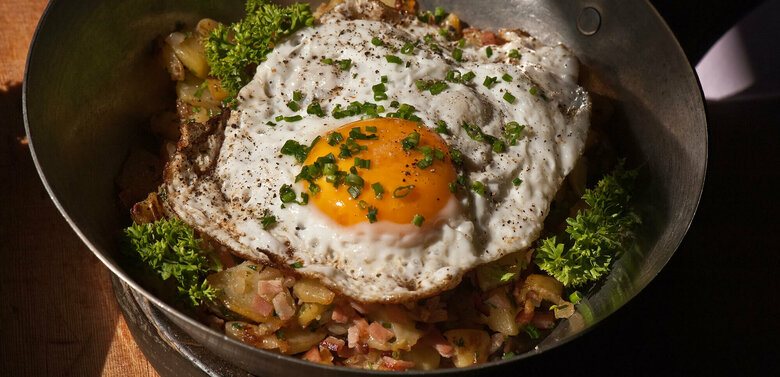 Tiroler Gröstl Tiroler Gröstl mit Spiegelei und Schnittlauch in einer kleine Eisenpfanne.
