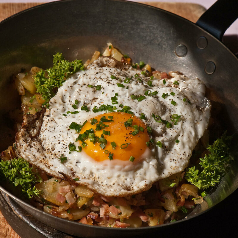 Tiroler Gröstl Tiroler Gröstl mit Spiegelei und Schnittlauch in einer kleine Eisenpfanne.