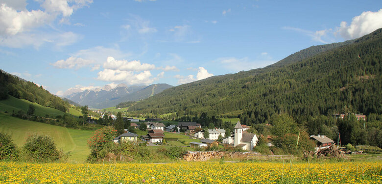 Arnbach Sillian Zu sehen ist die Ortschaft Arnbach mit einer blühenden Wiese im Vordergrund.