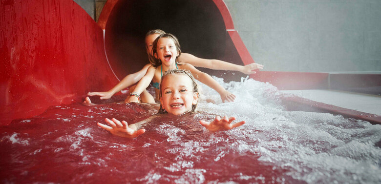 Dolomitenbad Lienz Drei Mädchen am Ausgang einer roten Wasserrutsche im Dolomitenbad in Lienz.