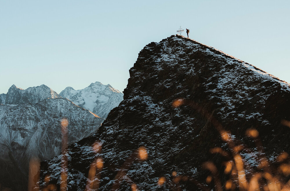 Figerhorn Wanderer am Gipfel des Figerhorns im Herbst mit schon einigen Schneefeldern auf den Bergen.