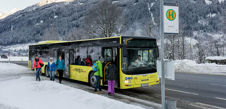 Bus Winter Gelber Bus hält an einer Bushaltestelle im Winter und lässt Fahrgäste ein- und aussteigen.