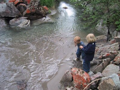 Wasserwanderweg Kinder auf dem Wasserwanderweg im Bergwasserparadies Defereggental. Sie stehen am Ufer eines Baches und blicken in den niedrigen, von Fels umgebenen Wasserspiegel.