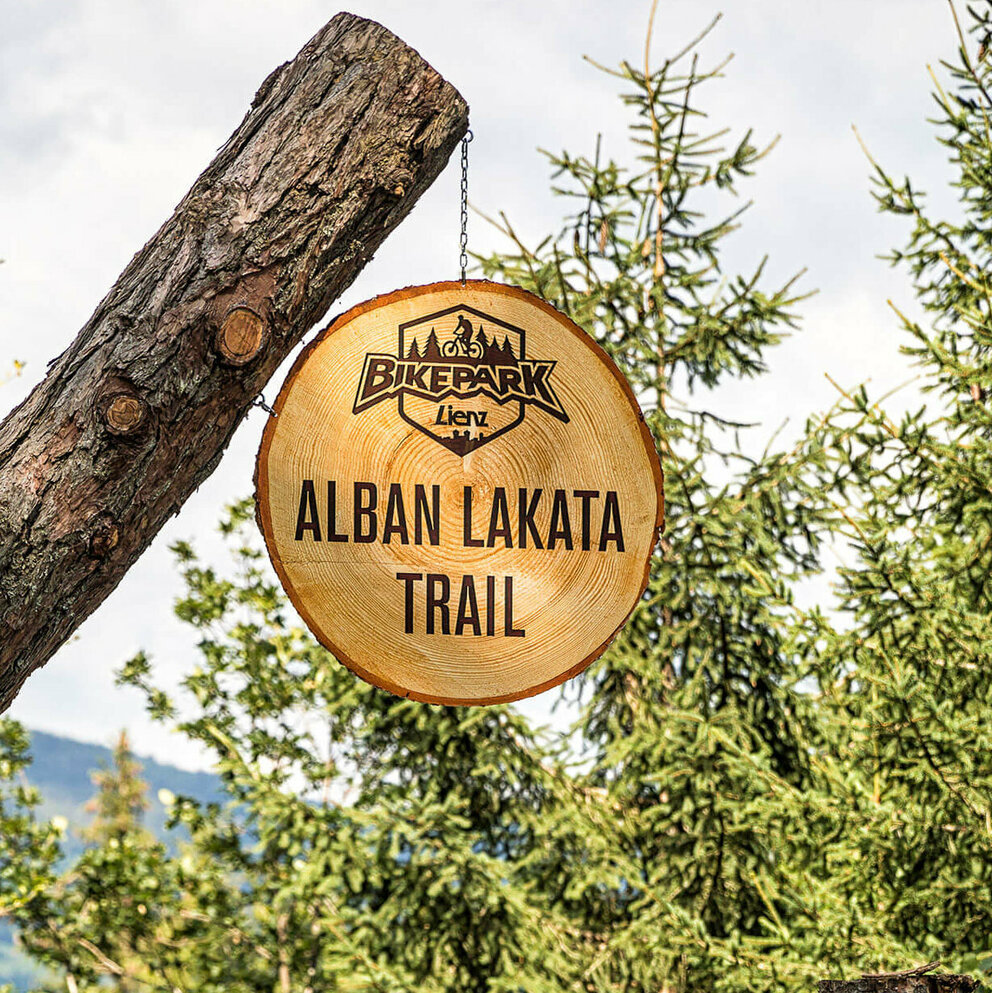 Alban Lakata Trail Bikepark Lienz Zwei Radfahrer mit roter Bekleidung und gelben Helmen am Eingang des Alban Lakata Trails im Bikepark Lienz.