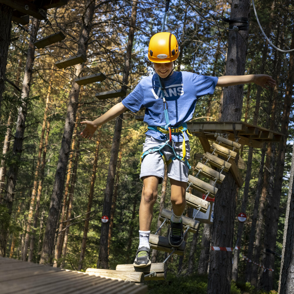 junger Kletterer im Kletterpark Moosalm Ein junger Kletterer zeigt seine Geschicklichkeit im Kletterpark Moosalm in Lienz in Osttirol.