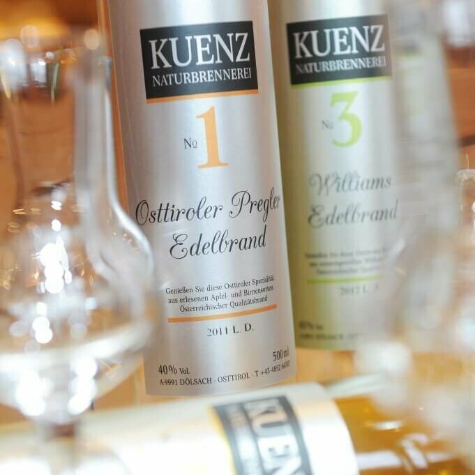 Osttiroler Pregler Vor zwei Flaschen Osttiroler Pregler liegt eine Flasche und davor ist ein leeres Schnapsglas anschaulich positioniert.