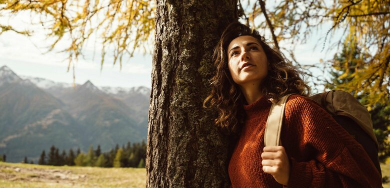 Wandern Zedlacher Paradies Frau lehnt sich im Zedlacher Paradies an einen vom Herbst gelb verfärbten Baum.
