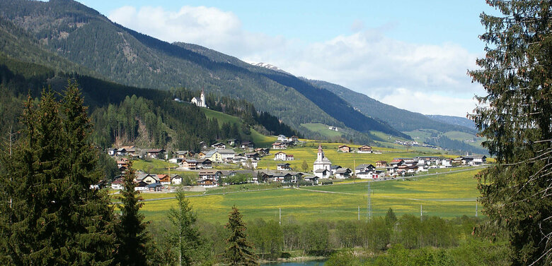 Ortsansicht Strassen Ortsansicht Strassen im Sommer mit dem sich hinter den Dorf erhebenden Wald und den grünen Feldern vor dem Dorf.