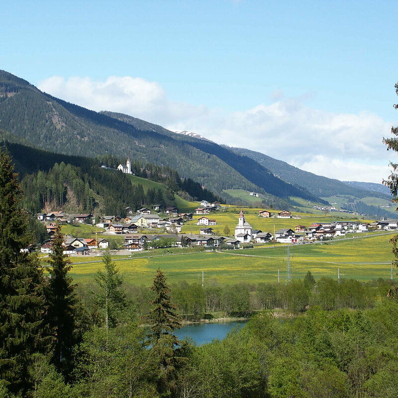 Ortsansicht Strassen Ortsansicht Strassen im Sommer mit dem sich hinter den Dorf erhebenden Wald und den grünen Feldern vor dem Dorf.
