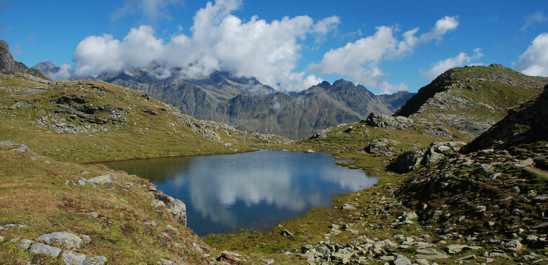 Neualpenseen Zettersfeld Einer der Neualpenseen am Lienzer Zettersfeld, im Vordergrund der klare Bergsee, im Hintergrund ein mächtiges Bergmassiv unter blauem Himmel.