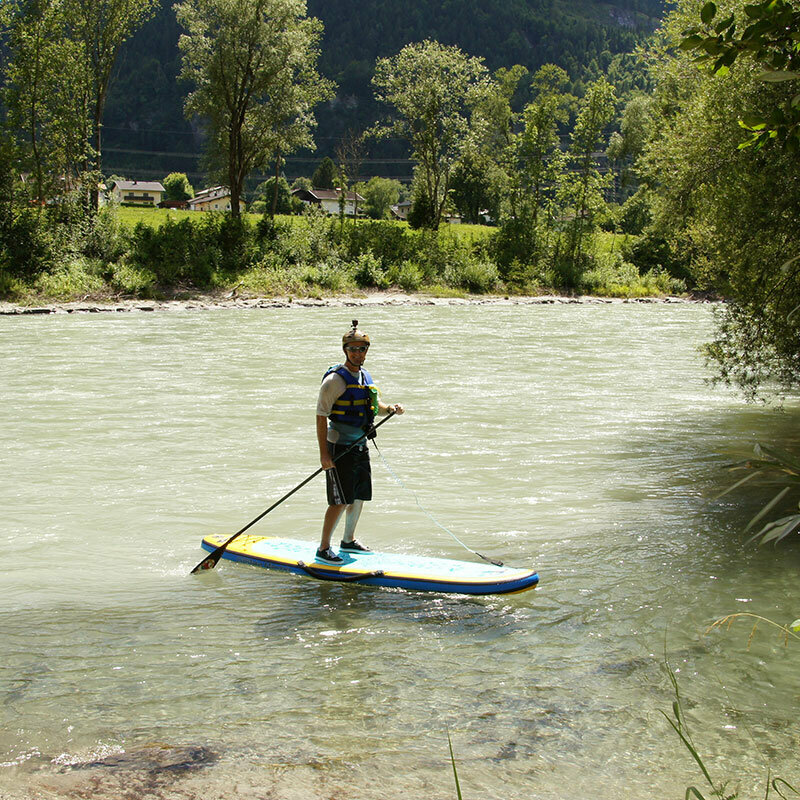Stand Up Paddle Eine Person mit Schwimmweste und Helm steht auf einem Stand Up Paddle Board auf der Isel.