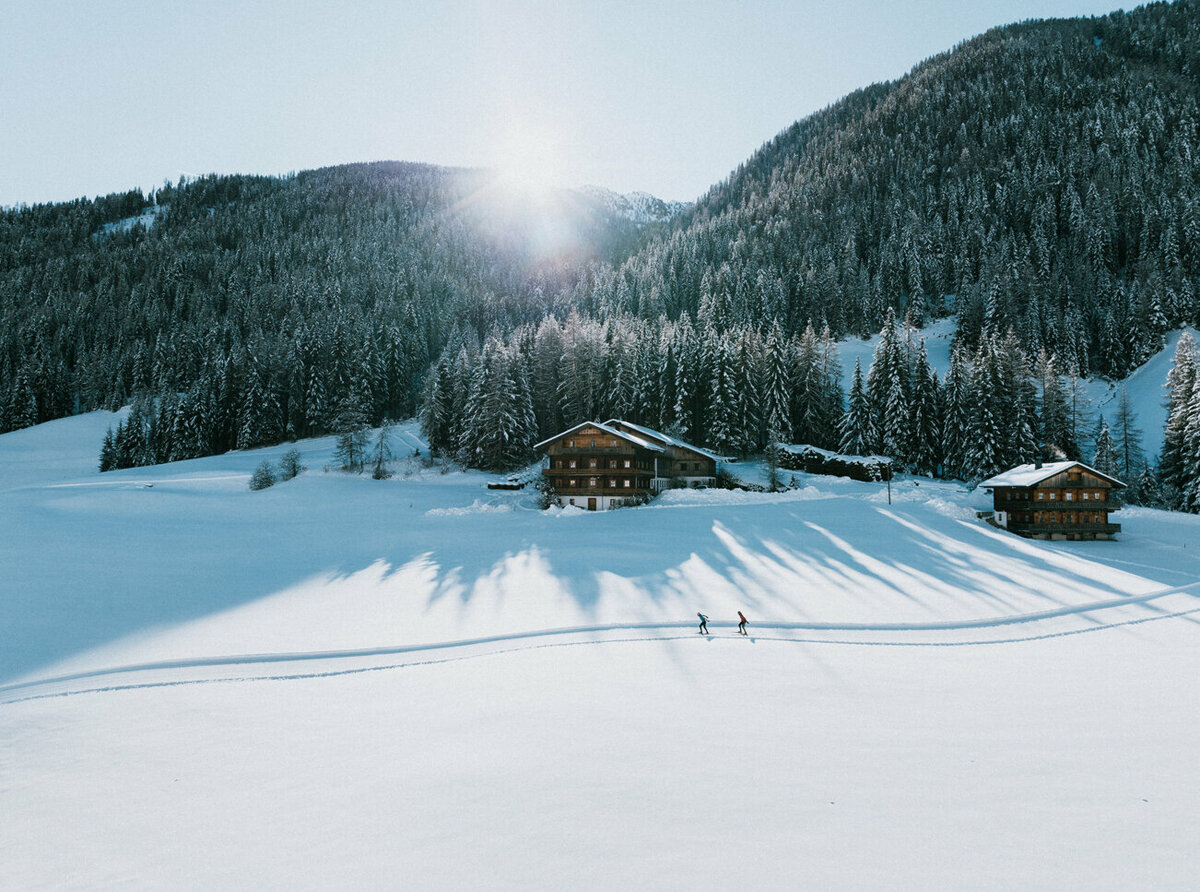 Langlaufloipe in Innervillgraten bei strahlendem Sonnenschein und eine frisch verschneitem Wald im Hintergrund