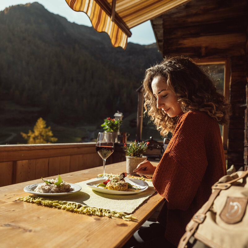 Schlipfkrapfen Unterstaller Alm Eine Frau genießt eine Portion Schlipfkrapfen auf der Terasse der Unterstaller Alm