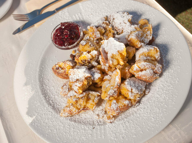 Kaiserschmarren Kaiserschmarren mit Preiselbeeren in einem separaten Schüsselchen auf einem weißen Teller.
