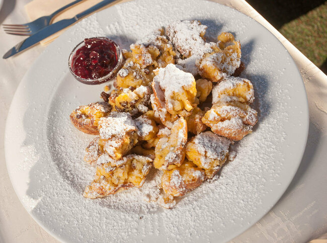 Kaiserschmarren Kaiserschmarren mit Preiselbeeren in einem separaten Schüsselchen auf einem weißen Teller.