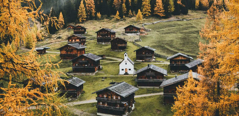 Almhüttendorf "Oberstalleralmen in Innvervillgraten" in herbstlicher Umgebung mit kleiner Kapelle im Zentrum; im Vordergrund goldgelbe Lärchen in Herbstfärbung Almhüttendorf "Oberstalleralmen in Innvervillgraten" in herbstlicher Umgebung mit kleiner Kapelle im Zentrum; im Vordergrund goldgelbe Lärchen in Herbstfärbung