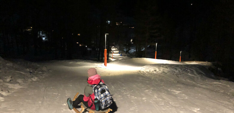 Nachtrodeln Kind beim Nachtrodeln bei beleuchteter Rodelbahn