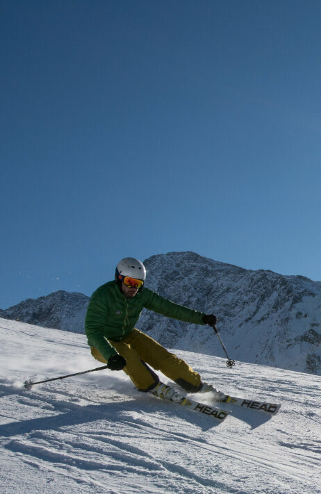 Skizentrum St. Jakob Ein Skifahrer mit grüner Jacke und gelber Hose carvt über die Pisten im Skizentrum St. Jakob im Defereggental bei Kaiserwetter.
