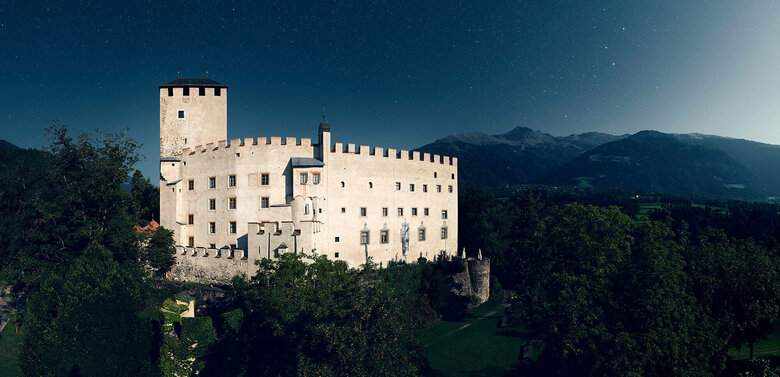 Schloss Bruck Lienz Aussenaufnahme bei Nacht von Schloss Bruck in Lienz mit Bergkulisse und Sternenhimmel im Hintergrund.