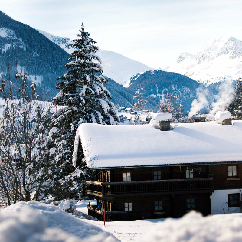 Defereggental Blick auf eine verschneite, dunkle Holzhütte im Winter im Defereggental.