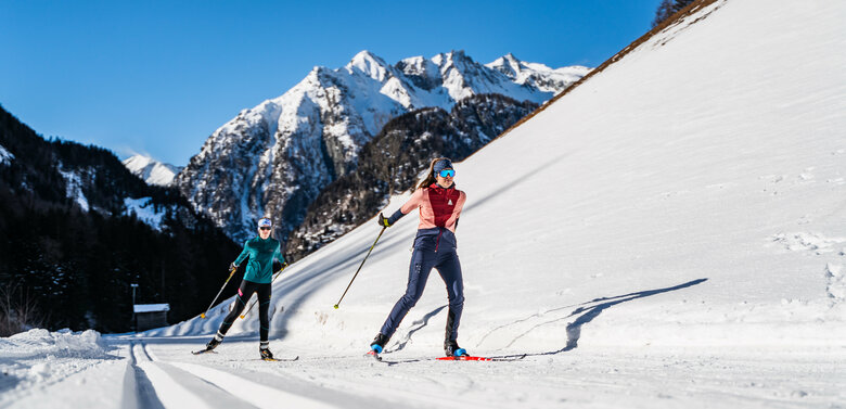 Langlaufen in Prägraten am Großvenediger mit Bergkulisse Aufnahme von unten von zwei skatenden Langläuferinnen über eine Loipe in Prägraten am Großvenediger mit Bergkulisse im Hintergrund.