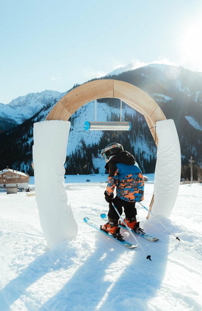Skifahren durch Bogen Obertilliach Kleiner Skifahrer fährt durch Bogen im Kinderland Obertilliach