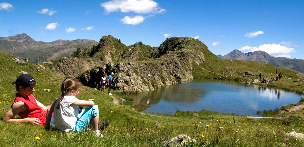 Wandern am Thurntaler Familie beim Wandern genießt das strahlende Wetter bei einem Bergsee am Thurntaler
