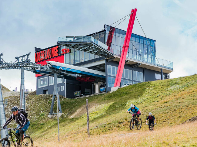 GG Resort Kals Matrei Adler Lounge Zwei talwärts fahrende Mountainbiker unterhalb der Bergstation der Gondelbahn im Großglockner Resort Kals-Matrei