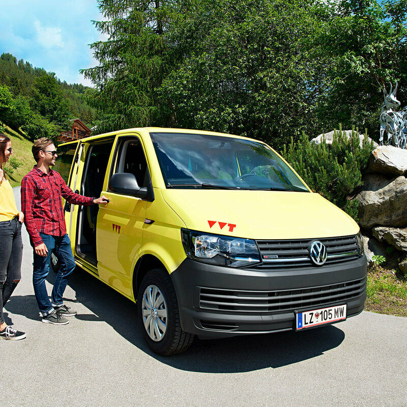 Gratisbus Auf dem Bus sind zwei Wanderer zu sehen, die gerade in das gelbe Wanderbus einsteigen