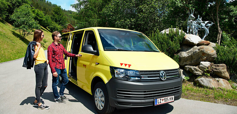 Gratisbus Auf dem Bus sind zwei Wanderer zu sehen, die gerade in das gelbe Wanderbus einsteigen