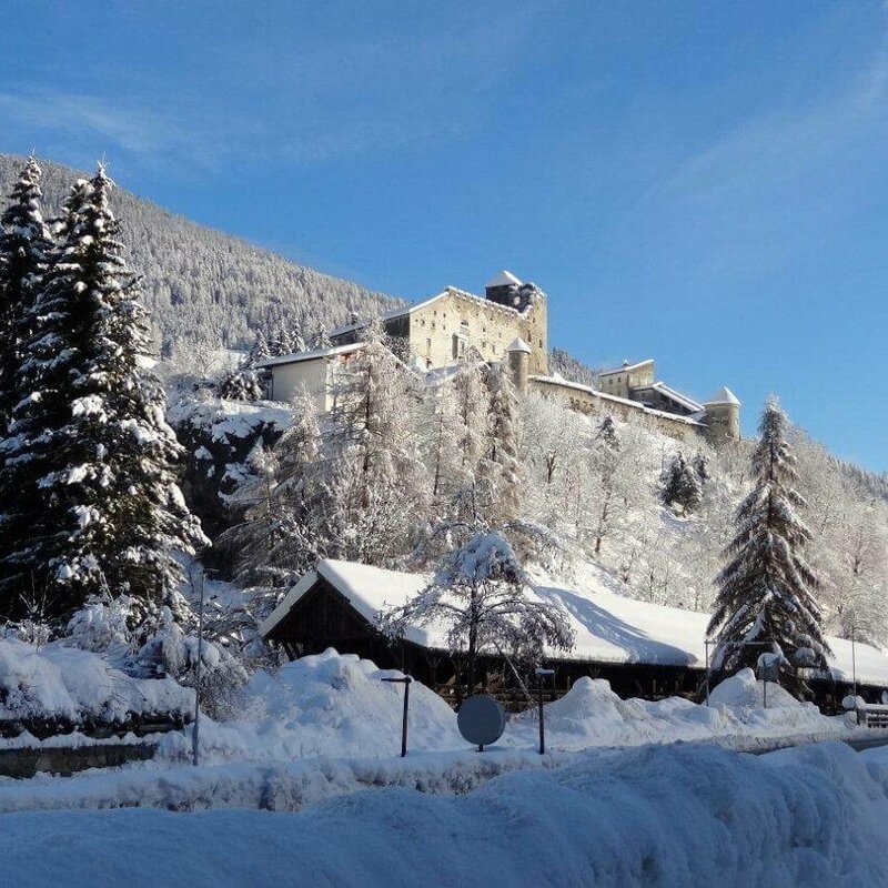Burg mit Punbrugge Winterliche Landschaft mit der Punbrugge im Vordergrund und der Burg Heinfels im verschneiten Wald im Hintergrund.