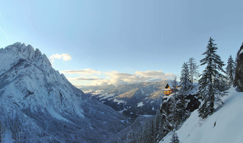 Dolomitenhütte Panorma Panoramablick auf die beleuchtete Dolomitenhütte im Winter. Die Landschaft ist tief verschneit.
