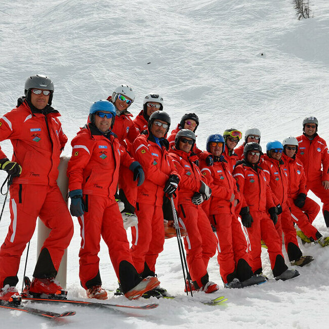 Wintersportschule Hochpustertal Team der Skischule White Element im Skizentrum Hochpustertal mit ihren auffälligen roten Skianzügen auf der Piste.