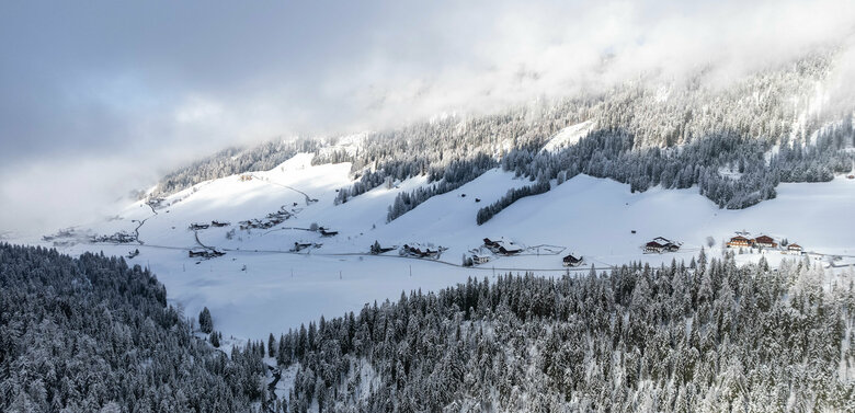 Die Kartitscher Ortsteile Rauchenbach (rechts) und Sulzenbach (links) vom Aufstieg zur Öfenspitze aus betrachtet. Lufaufnahme des Tiroler Gail- und Lesachtales bei herrlicher Winterstimmung mit frisch verschneiten Wäldern.