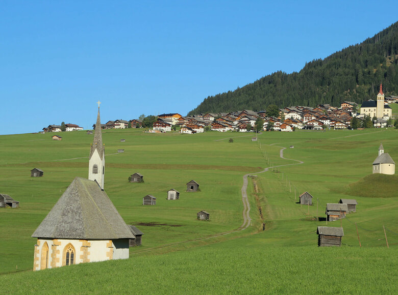 Obertilliach Blick von den Tilliacher Mösern auf das Dorf mit den saftig grünen Wiesen. Zwischen den unzähligen kleinen Heustadeln die 2 Kapellen St. Nikolaus und St. Helena.