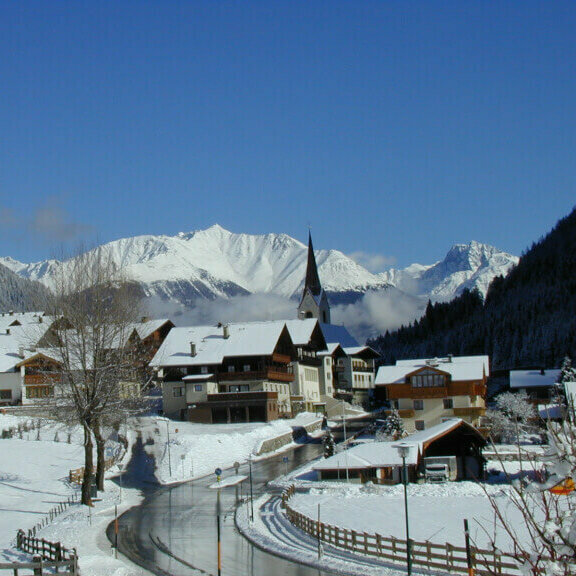 Hopfgarten Ein Blick auf das verschneite Hopfgarten i. D., im Hintergrund sind die Kirche und die Berge zu sehen.