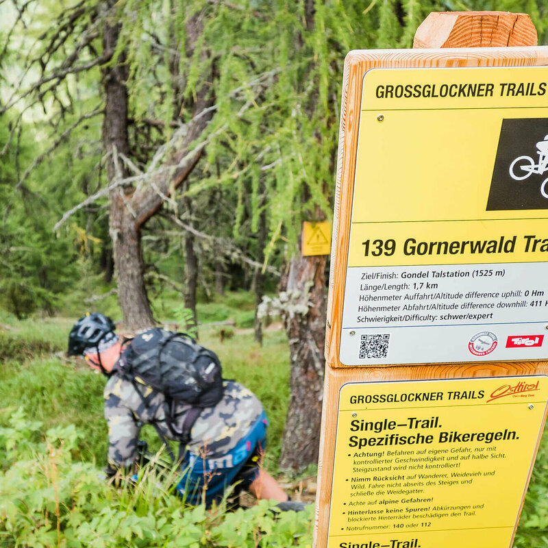 Mountainbiker bei einem Hinweisschild betreffend der Verhaltensreglen beim Biken