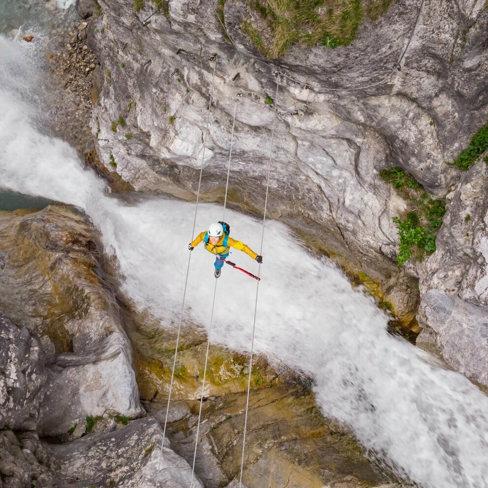 Galitzenklamm Klettern Eine Frau mit gelber Jacke geht über eine luftige Seilbrücke über den Fluss in der Galitzenklamm.