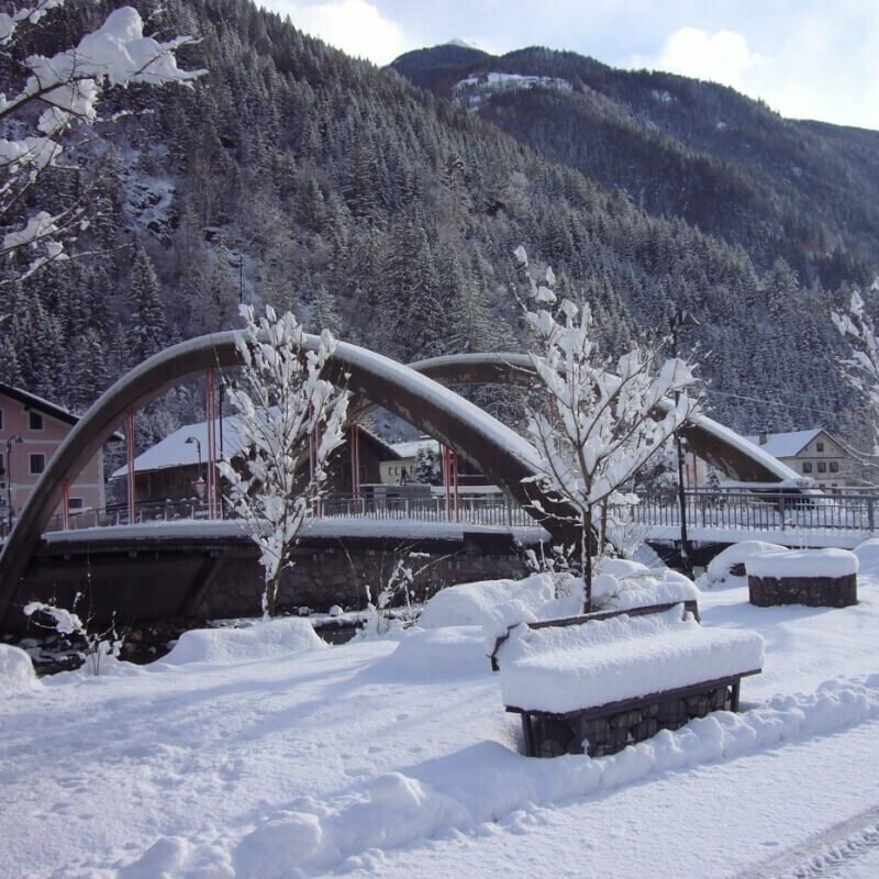 St. Johann Die Brücke in St. Johann mit viel Neuschnee und einem Wald im Hintergrund.